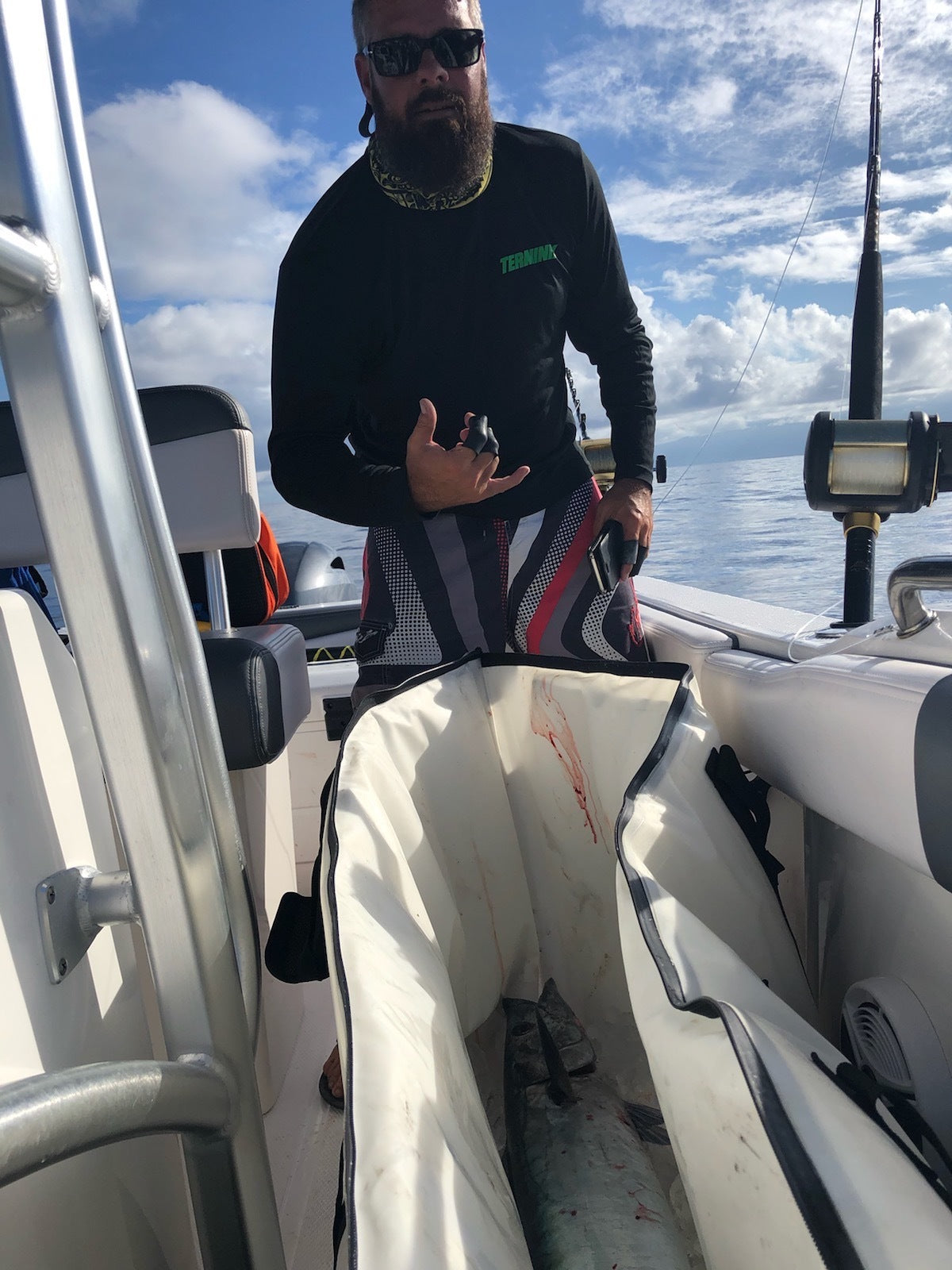 Fisherman placing a large saltwater fish into a white Topline soft ice bag on the dock.
